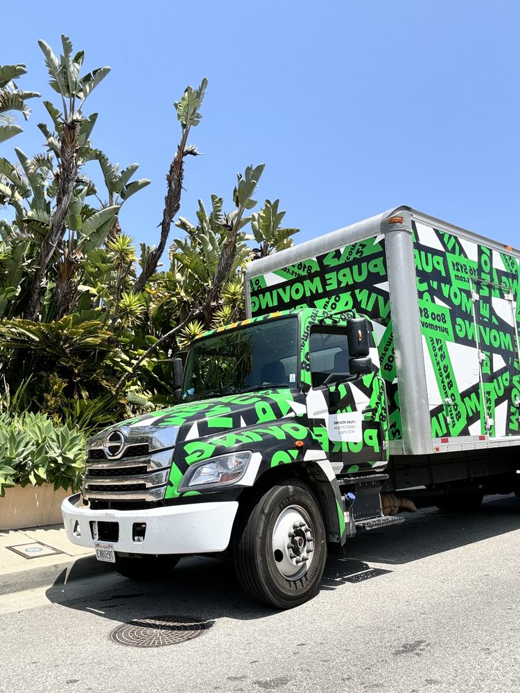 Pure Movers branded moving truck parked outside residential homes