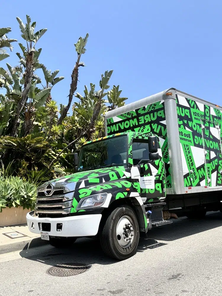 Pure Movers branded moving truck parked outside residential homes