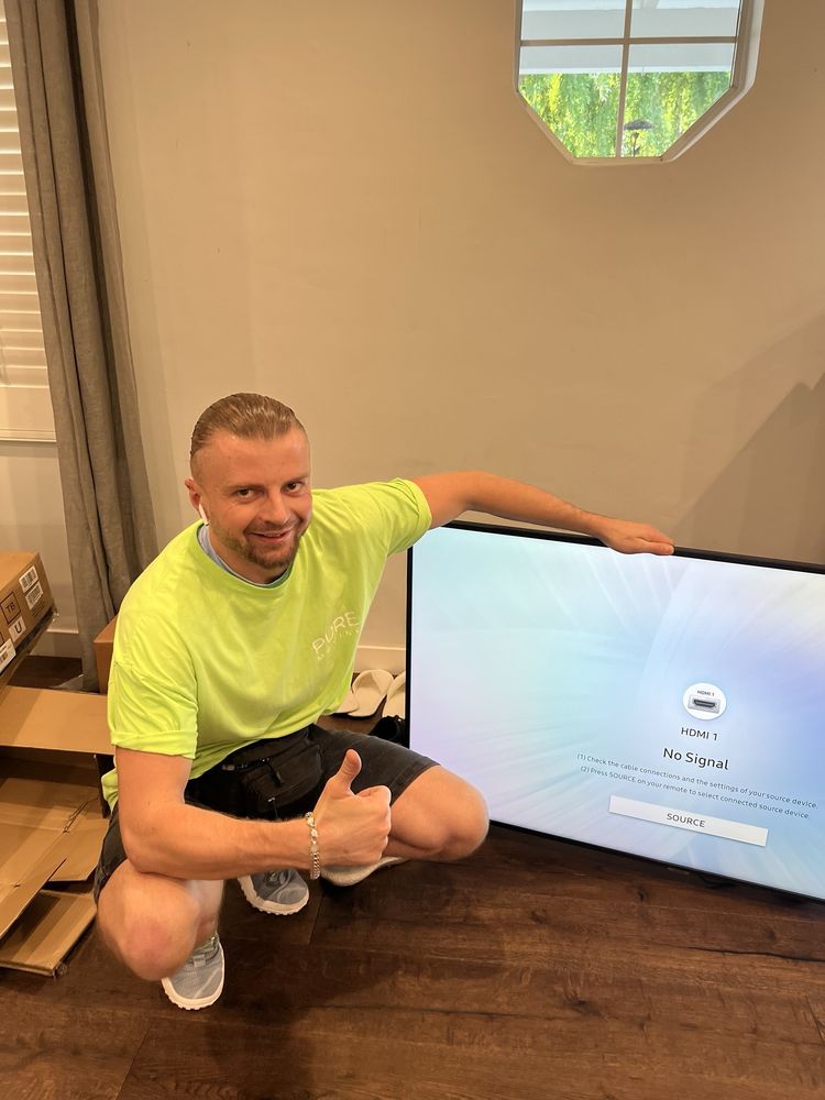 Pure Movers employee giving thumbs up beside delivered television