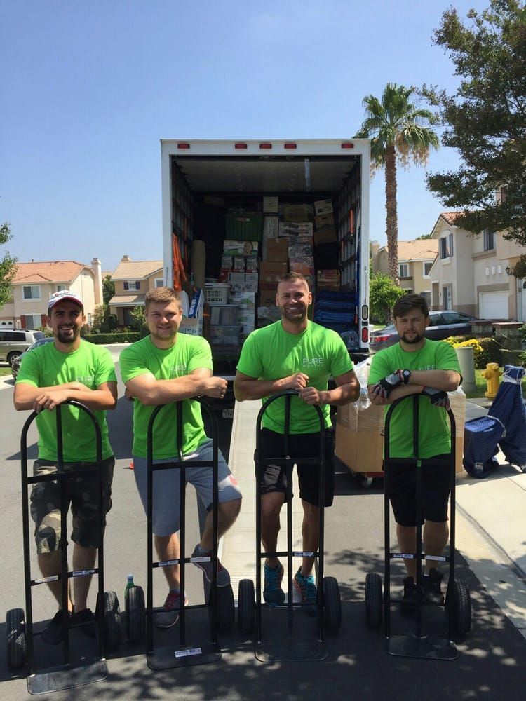 Pure Movers crew with moving dollies standing in front of a fully loaded moving truck