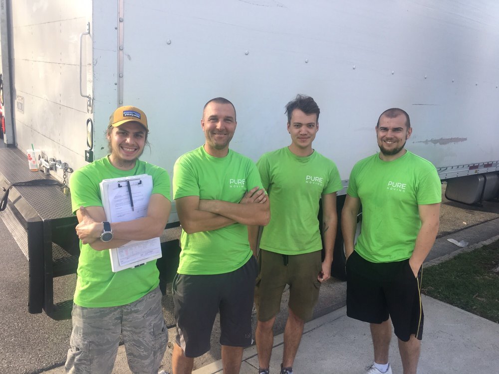 Pure Movers team members standing in front of a moving truck ready for a residential move