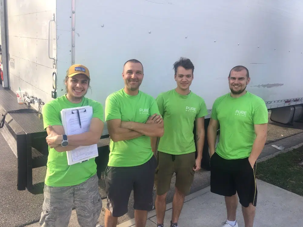 Pure Movers team members standing in front of a moving truck ready for a residential move