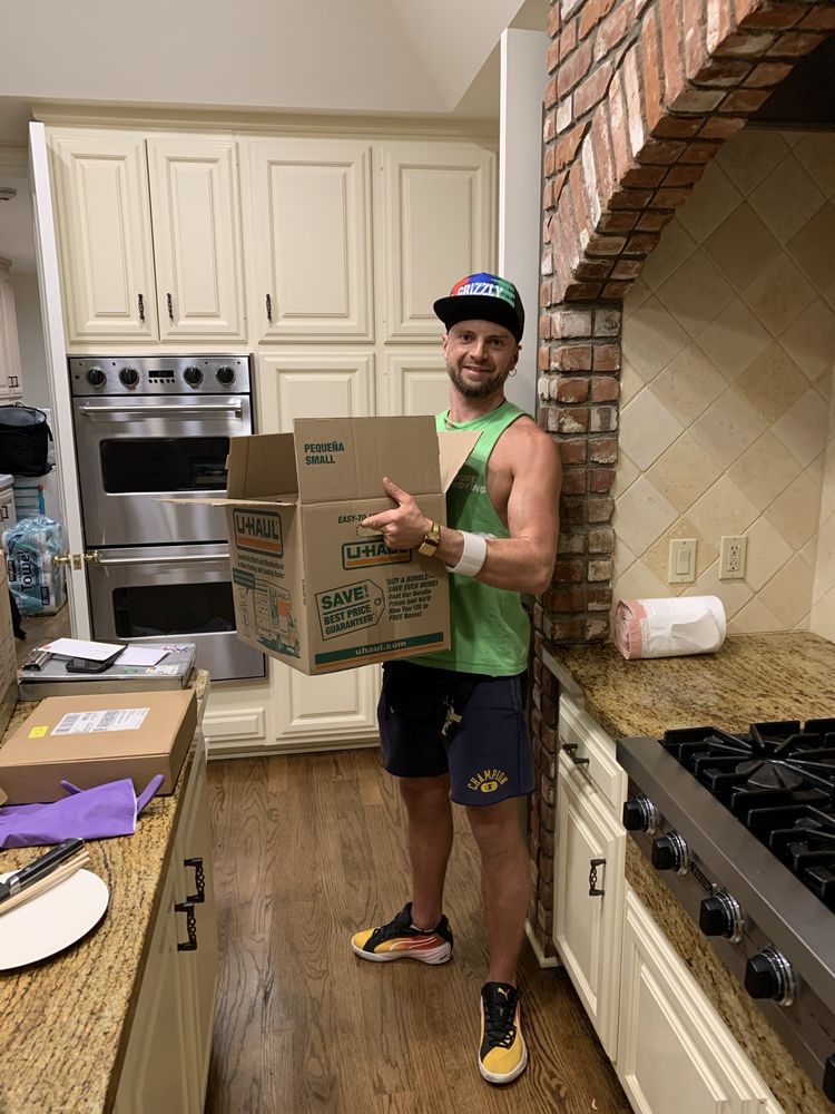 Pure Movers employee carrying moving box inside residential kitchen