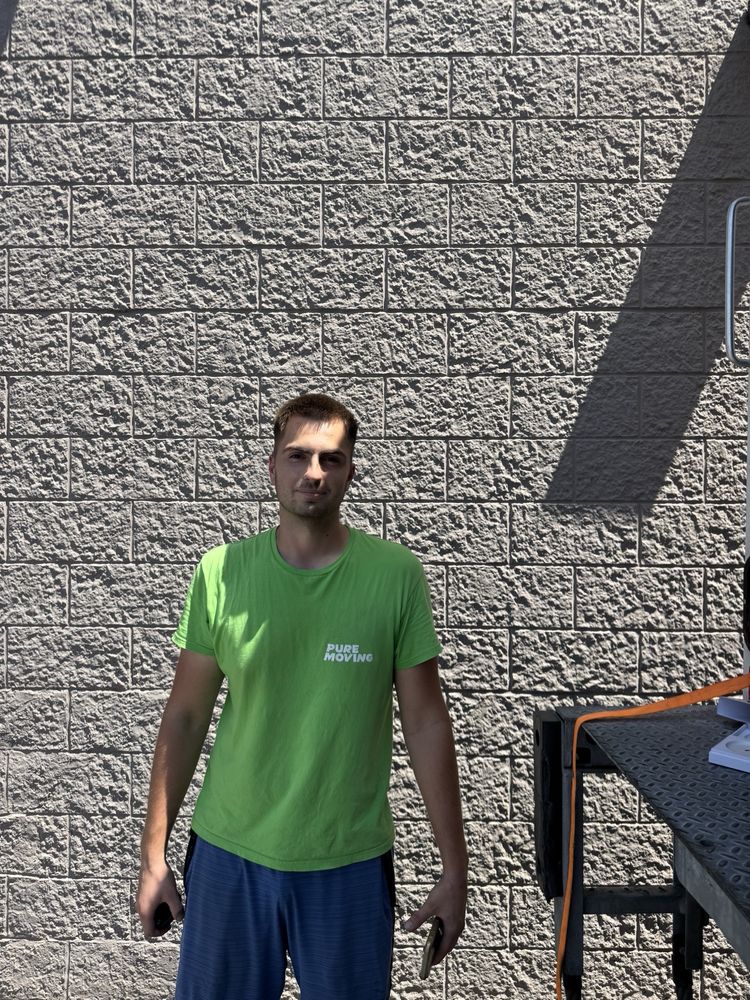 Pure Movers employee standing beside moving truck during relocation service