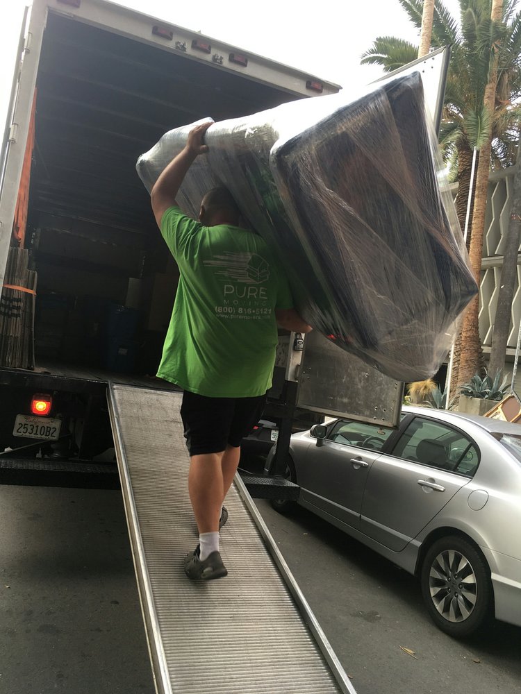 Mover carrying wrapped furniture into moving truck