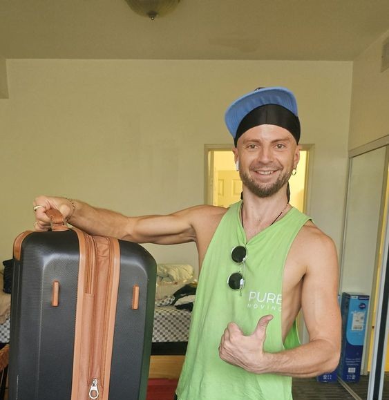 Professional mover carrying rolling suitcase inside apartment during relocation