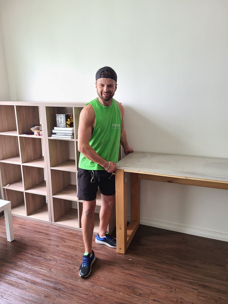 Professional mover positioning wooden desk inside residential home during move-in service
