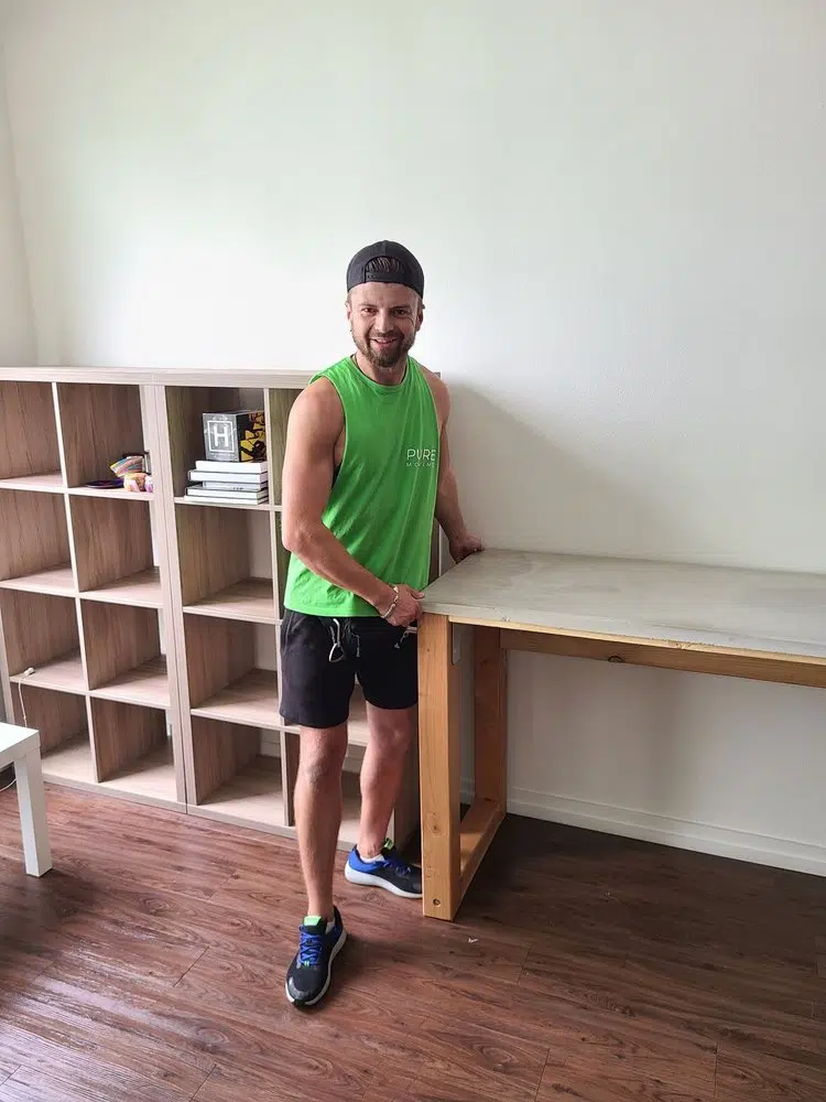 Professional mover positioning wooden desk inside residential home during move-in service