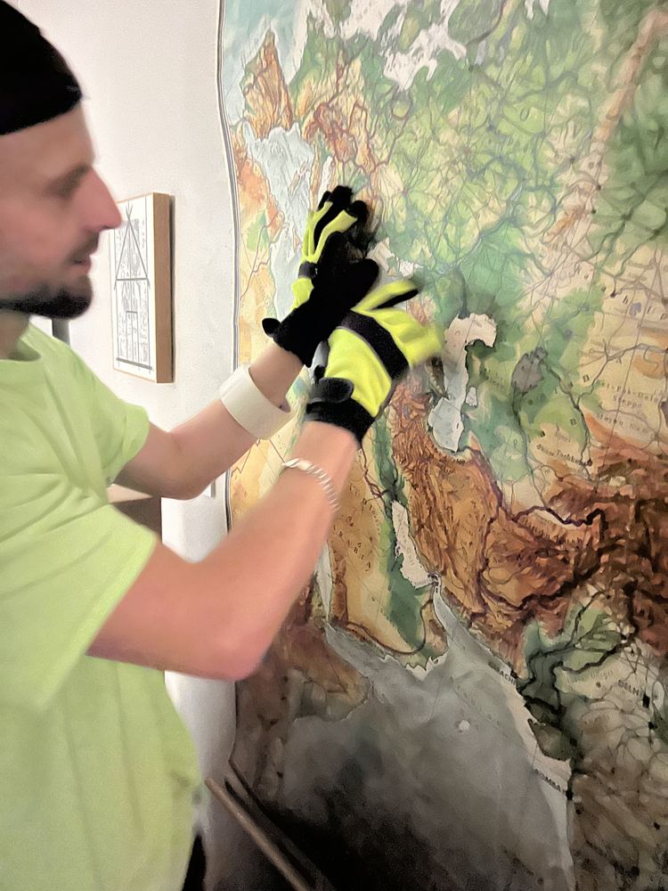 Mover wearing gloves while carefully adjusting framed wall artwork in home