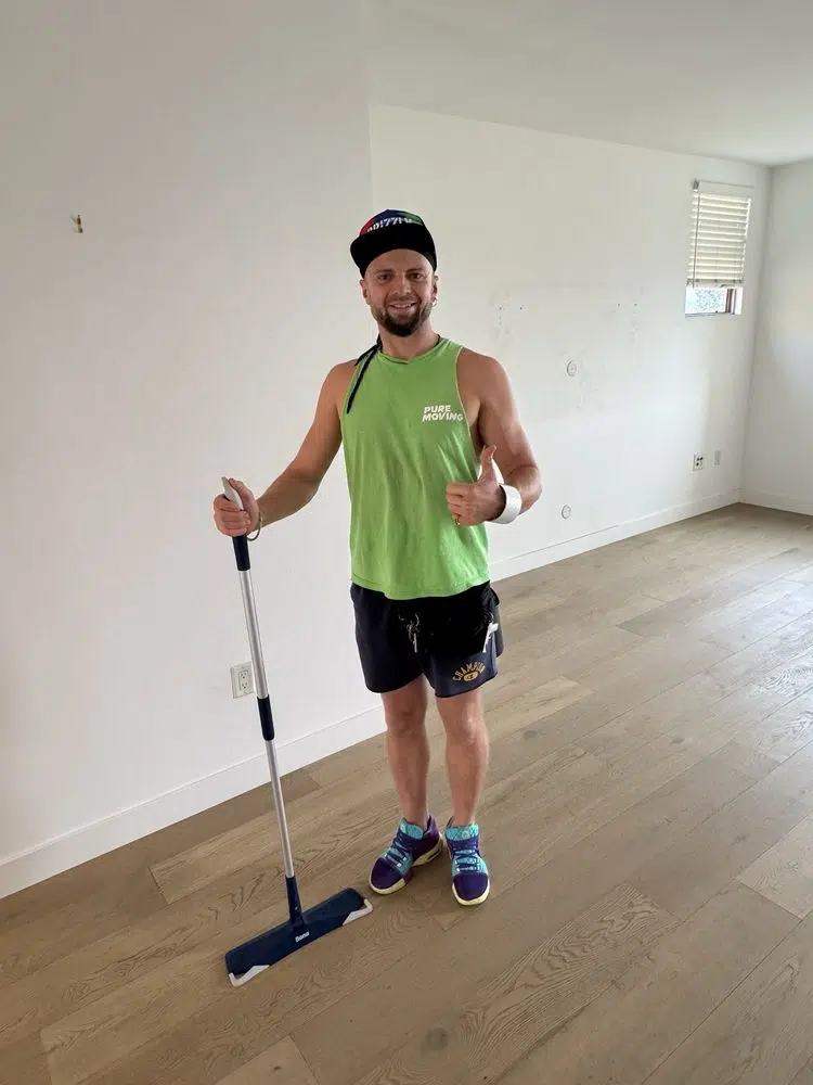 Professional mover cleaning empty room floor after residential move-out