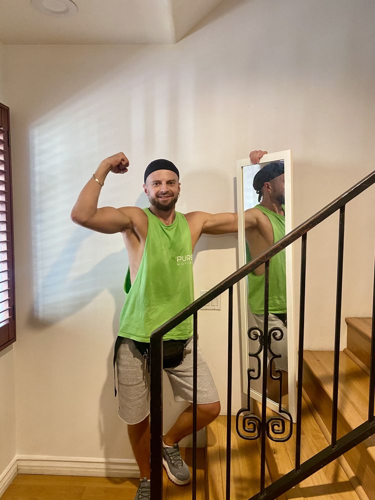 Strong mover posing beside staircase while handling mirror during home move