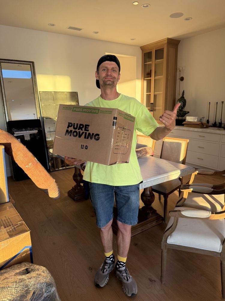 Professional mover standing beside stacked moving boxes inside modern home