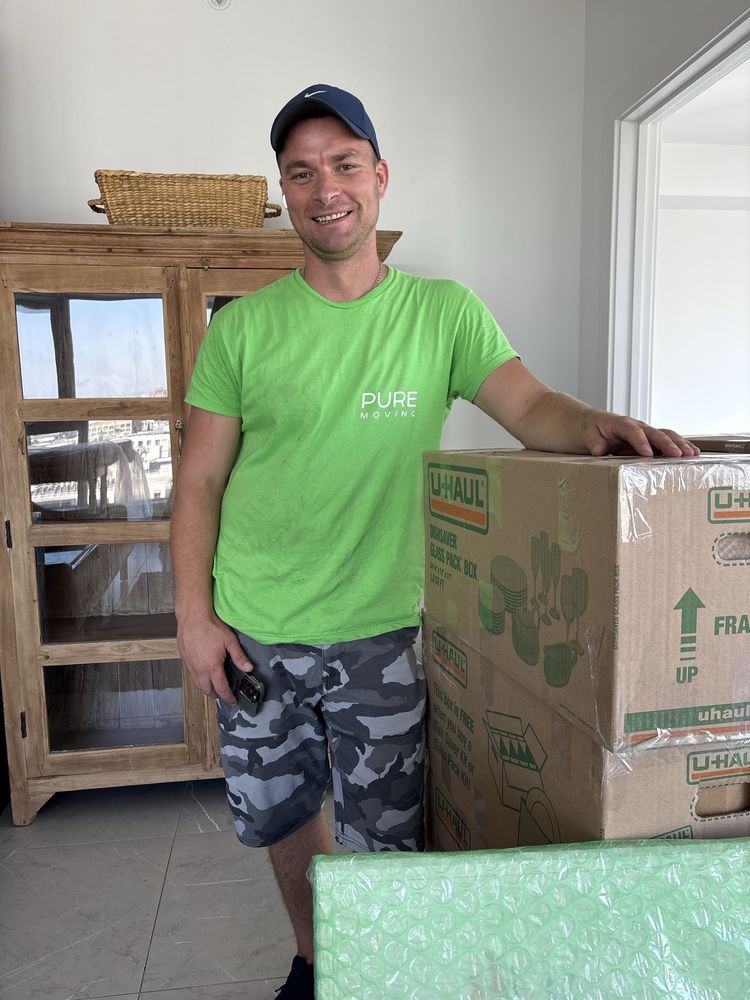 Professional mover standing beside packed moving boxes inside customer home