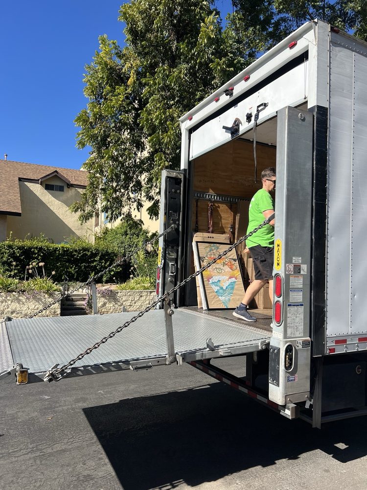 Professional mover loading furniture into a moving truck with liftgate in residential neighborhood