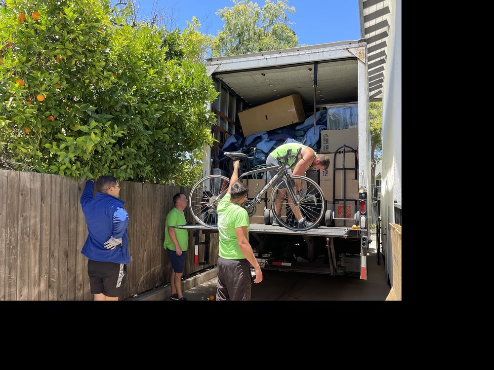 Moving team loading packed moving truck with bicycle and household belongings