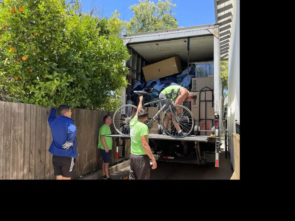 Moving team loading packed moving truck with bicycle and household belongings